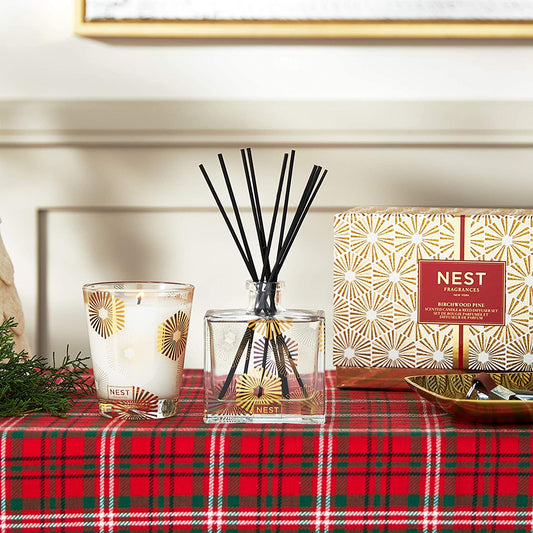 NEST New York Birchwood Pine Classic Candle & Reed Diffuser Set emitting warm, cozy woodsy fragrance for a festive home ambiance.